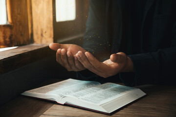 Wall Mural - Handsome man hands are praying for God's blessings on an open bible with window light Pray in the Morning. Power of hope or love and devotion.