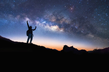 Wall Mural - Landscape with Milky Way. Night sky with stars and silhouette of a standing happy man on the mountain, Success or winner, leader concept. High iso with Noise.