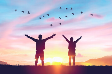 Couple rising hands and birds flying on sunset sky at nature field abstract background. Freedom feel good and travel adventure concept.