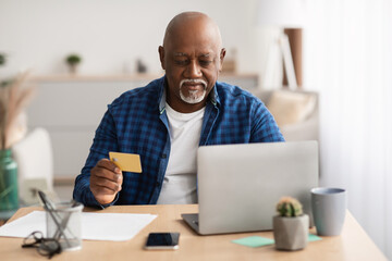 Wall Mural - Senior Black Businessman Shopping Online Using Laptop Sitting In Office