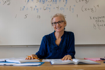 Portrait of high school math teacher sitting at desk working on assignments for students.