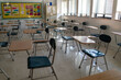 © Robert Peak - Desks in empty dark high, middle, or elementary school classroom with light coming through windows.