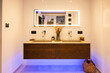 Modern oak double washbasin and concrete basin with modern faucets and lighted mirror in bathroom
