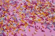 100s and thousands  sprinkles on doughnuts pink bright sugar strands background