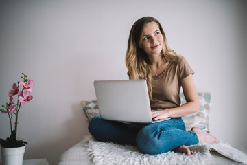 Caucasian female student dressed in casual clothing spending weekend leisure for laptop e learning, skilled hipster girl with modern netbook computer connecting to wireless internet in home interior