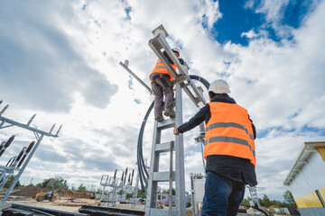 Two electrician builder workers installing high-voltage cable