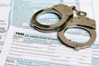 Income tax return documents and handcuffs. Tax evasion, crime and fraud concept.