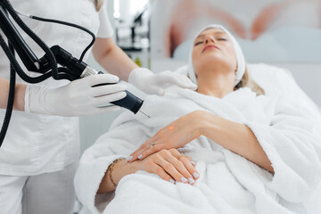 A young girl gets carbon peeling for the skin of her hands in a beauty salon. Laser pulses cleanse the skin. Hardware cosmetology. The process of photothermolysis, warming the skin.