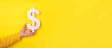 Hand Holding Dollar Symbol Over Yellow Background, Panoramic Layout