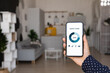 © fizkes - Smart home infographic graph on smartphone screen close up. Woman holding mobile phone, using app for electronic facility, digital device control in apartment. Internet of things, comfort in house