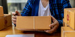 © kamiphotos - Asian person writing customer's shipping information on parcel box, He owns an online store, He ships products to customers through a private courier company. Online selling concept.