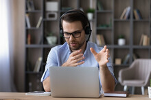 Businessman In Glasses And Headset Talking, Making Video Call Looking At Laptop Screen, Chatting Online Consulting Client Or Teacher Leading Educational Webinar, Young Man Engaged In Internet Meeting