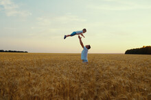 Father Throwing Little Son Up In The Air In Wheat Field In Slow Motion. Parent And Child Having Fun And Enjoying Time Together. Concept Of Happiness