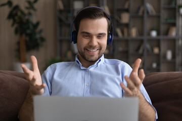 Wall Mural - smiling man in headphones using laptop, chatting online by video call, happy student or freelancer e