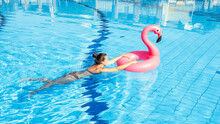 Summer Fun. Happy Young Sexy Girl In Bikini Swimsuit With Pink Flamingo Float In Blue Pool Water. Having Fun And Enjoying Travel Vacation. Swimming Pool Water.