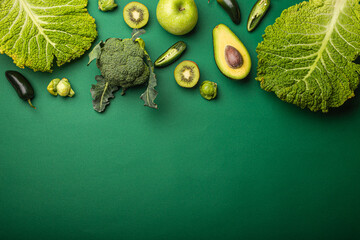 Creative layout food concept made of green fruit and vegetables on green background flat lay: avocado, kale, broccoli, Brussels sprouts, kiwi, peppers, apple, cabbage top view with space for text
