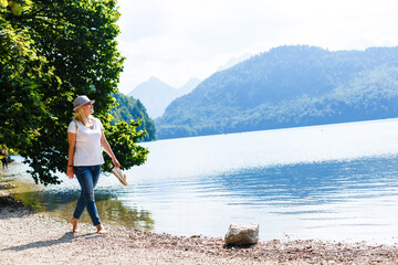 Young girl sitting near by beautiful lake . Original wallpaper from summer morning