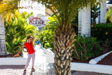 Wall Mural - The concept of family happiness and children in the summer on the sea among palm trees. Cute little girl without a pattern.