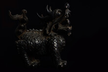 Dark Close-up Of An Old Chinese Dragon Figure Made Of Wood, Which Stands In Front Of A Dark Background And Already Shows Some Signs Of Wear