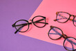 different eyeglasses on pink and purple geometric background, trendy eyeglass frames copy space