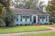 An old blue cottage style small older house with a front lawn and sidewalk