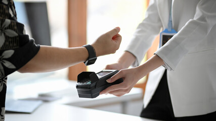 a man using his modern digital wristwatch paying his shopping.