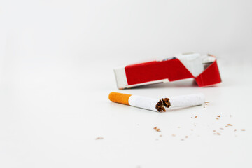 A pack of cigarettes on a white background and a broken cigarette in the foreground. Anti-smoking concept. harm of smoking
