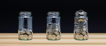 Money Savings, Investment, Financial Wealth Management Concept. Coin In Three Glass Jars On Wood And Black Background. Business Financial And Saving Money And Investments Fund Growth Concept.
