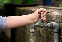 Hand From A Child Is Turning Tap Water Valve