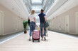 © H_Ko - Couple walking with luggage along the hotel corridor