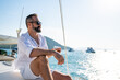 © CandyRetriever  - Caucasian man enjoy outdoor luxury lifestyle with alcoholic drinks while catamaran boat sailing at summer sunset. Handsome male relaxing outdoor leisure activity with tropical travel vacation trip