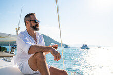Caucasian Man Enjoy Outdoor Luxury Lifestyle With Alcoholic Drinks While Catamaran Boat Sailing At Summer Sunset. Handsome Male Relaxing Outdoor Leisure Activity With Tropical Travel Vacation Trip