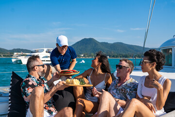 group of caucasian people friends enjoy luxury outdoor party eating fresh fruit together while catam