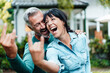 © Westend61 - Cheerful making couple gesturing horn sign in backyard