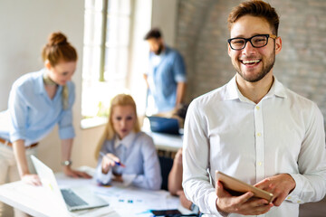 Wall Mural - Portrait of happy successful business people working on tablet in office. Business teamwork concept