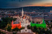Budapest, Hungary - Aerial View The Famous Illuminated Fisherman's Bastion (Halaszbastya) And Matthias Church Lit Up With National Red, White And Green Colors On A Summer Night At Dusk
