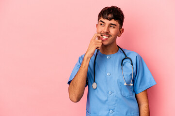 Wall Mural - Young mixed race nurse man isolated on pink background relaxed thinking about something looking at a copy space.