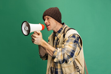 Poster - Studio shot of young man, fisherman with fishing accessories, fish rod wearing sport style clothes isolated over green background