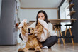 © diignat - Lovely woman playing with her dog and taking care covering it in a blanket and hugging the pet at home