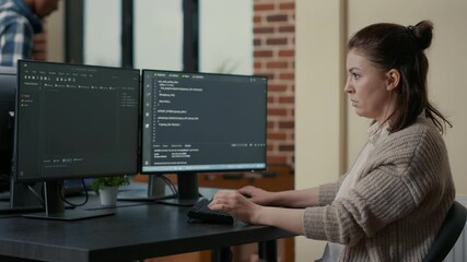 portrait of focused programer writing code looking at multiple computer screens displaying programmi