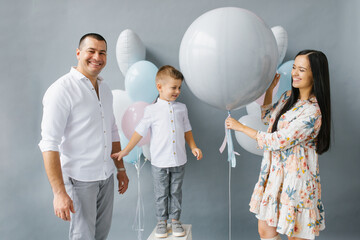 Gender reveal party. Stylish beautiful family with a baby pop a balloon to find out the gender of the unborn child in the family