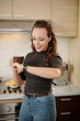 © DragonImages - Smiling woman drinking morning coffee and checkng time on smartwatch