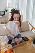 © DragonImages - Hungry young woman eating tasty sandwich and checkng e-mails on laptop