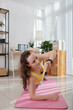 © DragonImages - Young woman exercising on yoga mat and checking notifications on smartwatch