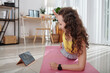 © DragonImages - Active young woman exercising on yoga mat during online meeting with colleagues