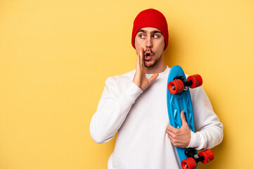 Wall Mural - Young skater caucasian man isolated on yellow background is saying a secret hot braking news and looking aside