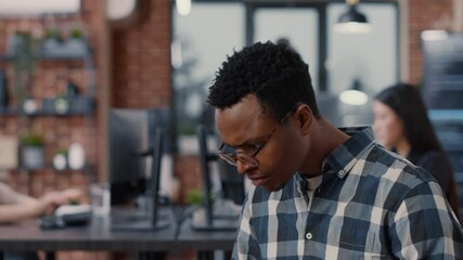 Portrait of app developer sitting down looking at laptop screen and looking up smiling at camera in server room. System engineer using portable computer developing machine learning software.