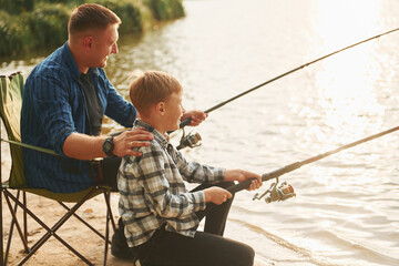 Wall Mural - Resting and having fun. Father and son on fishing together outdoors at summertime