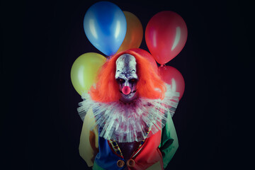 Wall Mural - Terrifying clown with air balloons on black background. Halloween party costume