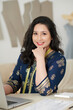 © DragonImages - Portrait of cheerful Indian tailor in traditional dress working on laptop in her atelier